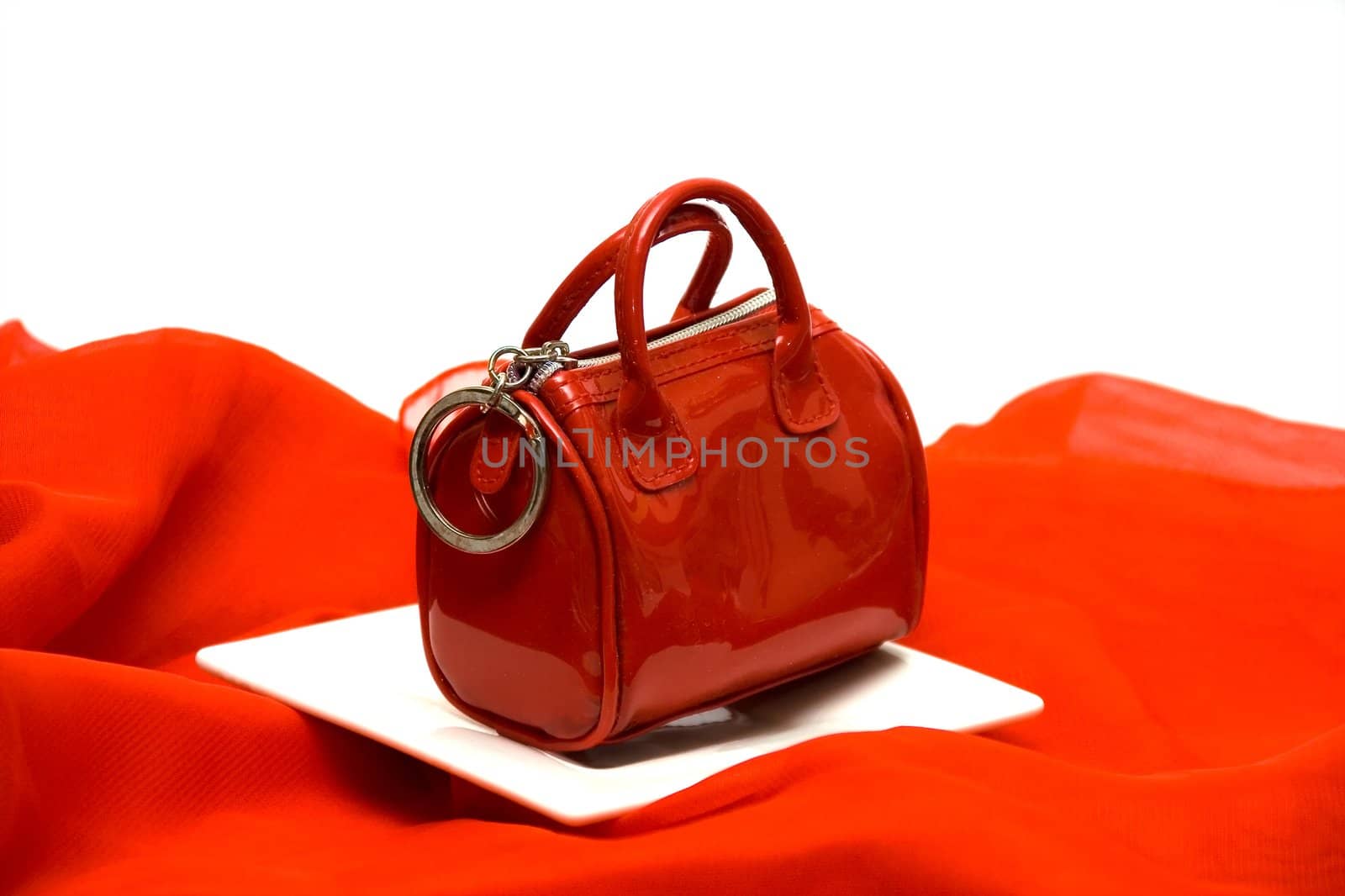 Red elegant female handbag the beautician on a red fabric among white ware