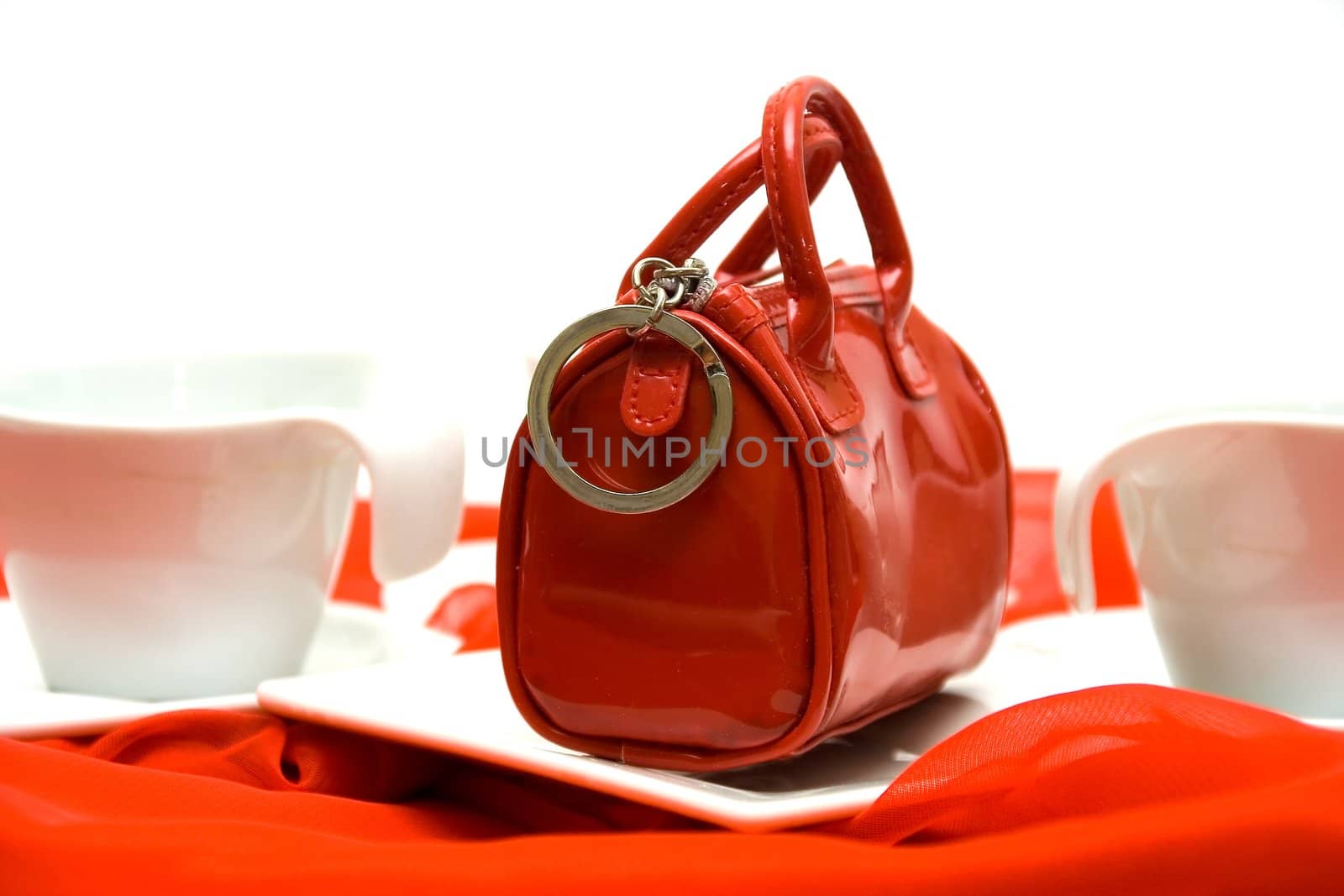 Red elegant female handbag the beautician on a red fabric among white ware