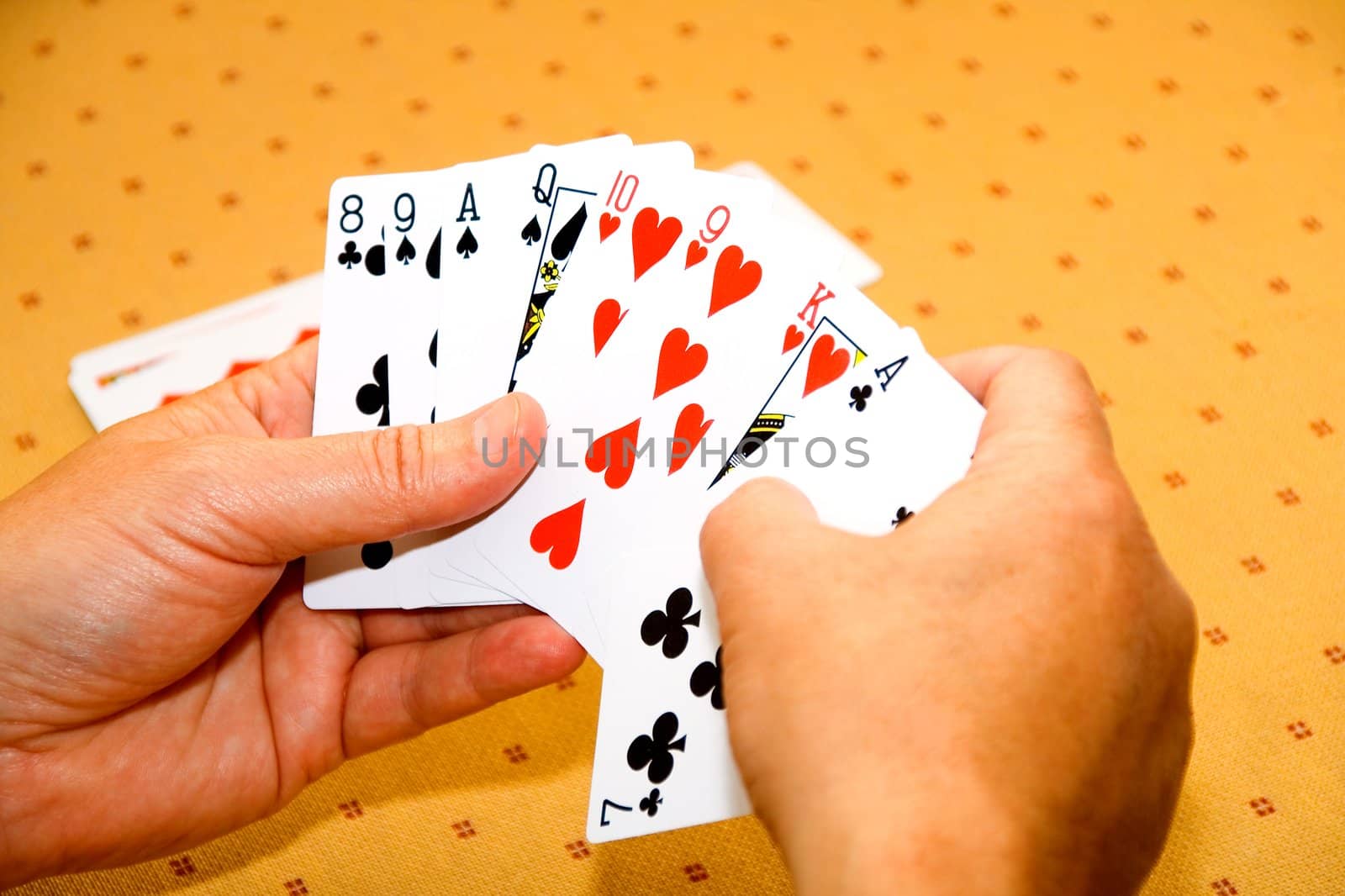 Hands of the player with playing cards on a game table