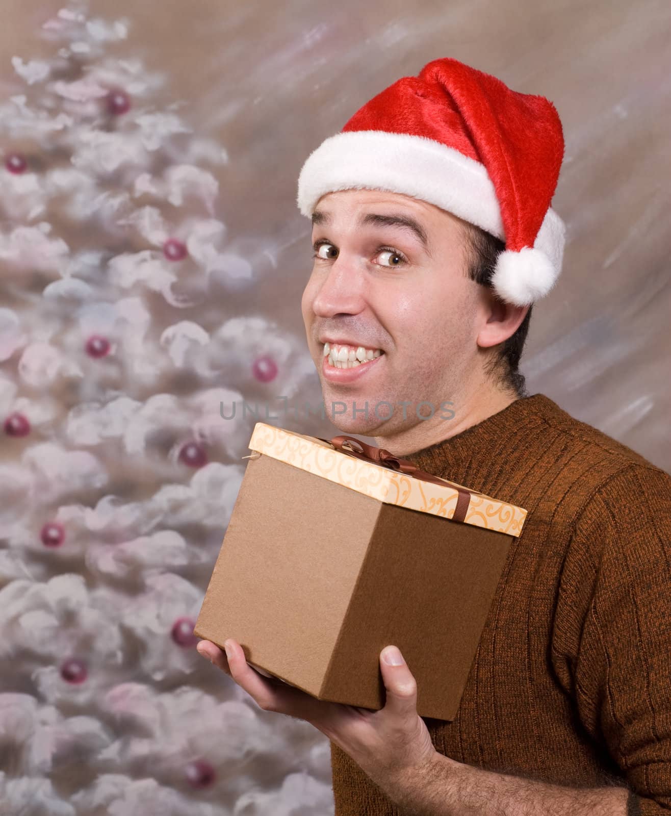 A happy man holding a Christmas present and smiling in front of a hand painted xmas background