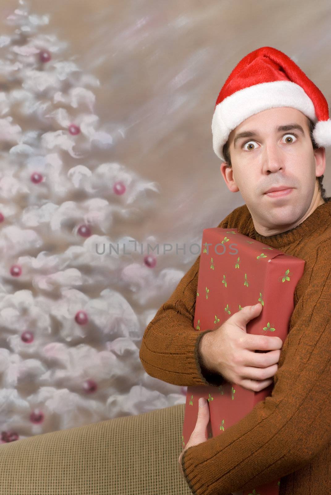 A young man is being greedy and holding a Christmas present close to his chest