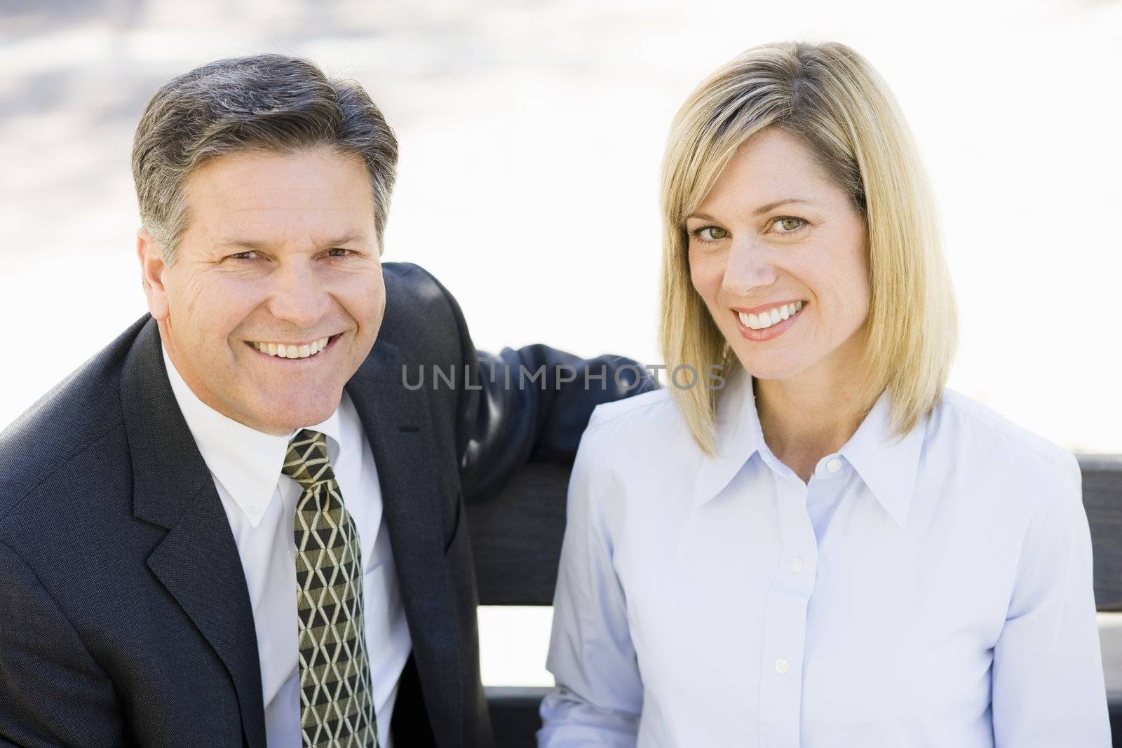 Portrait of a Businesswoman and a Businessman Sitting on a Bench Outdoors