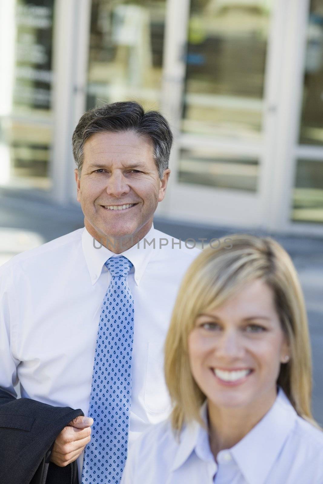 Businesswoman and Businessman Standing Outdoors Smiling To Camera