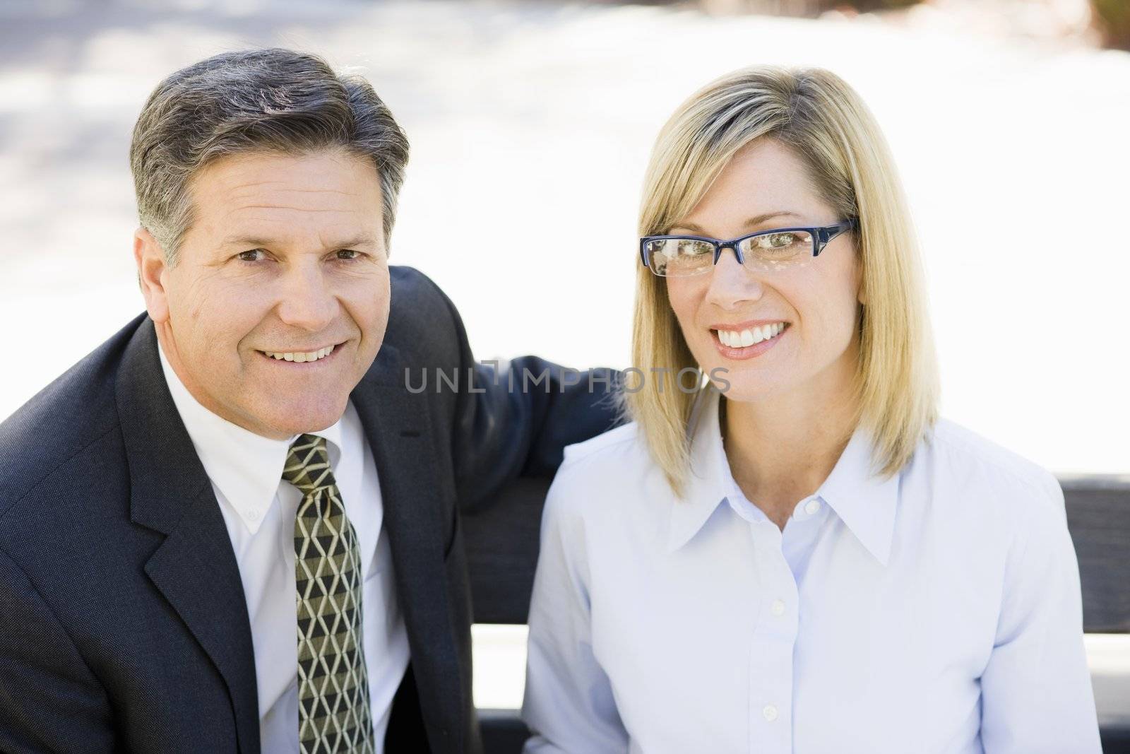 Portrait of a Businesswoman and a Businessman Sitting on a Bench Outdoors