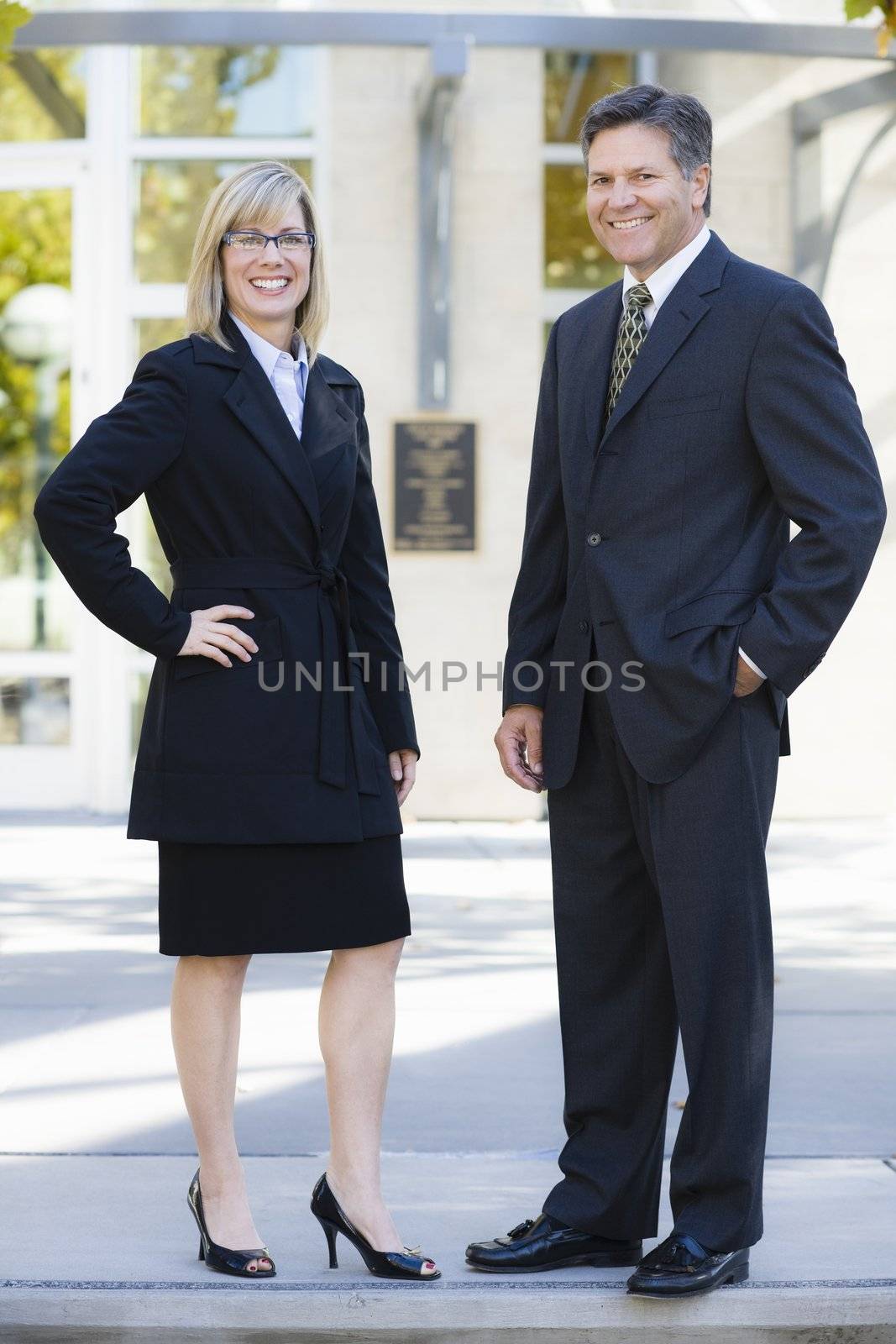 Businesswoman and Businessman Standing Outdoors Smiling To Camera