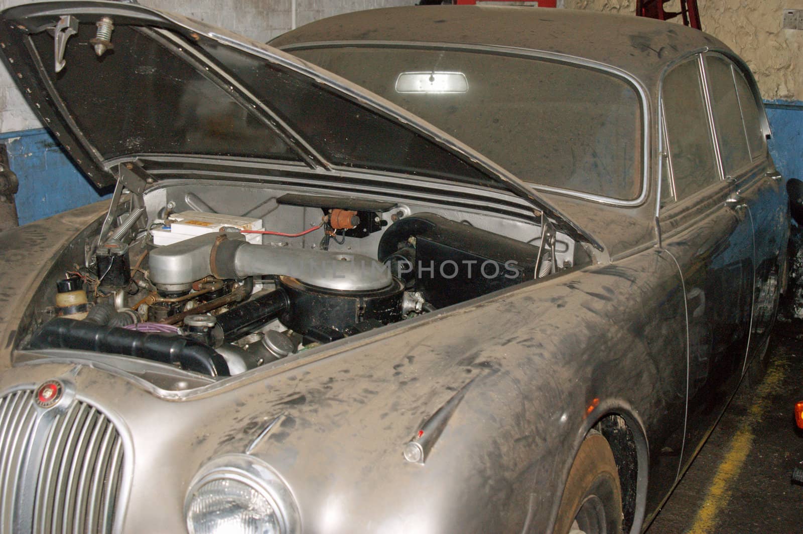 An old british classic car covered in dust sitting in a garage