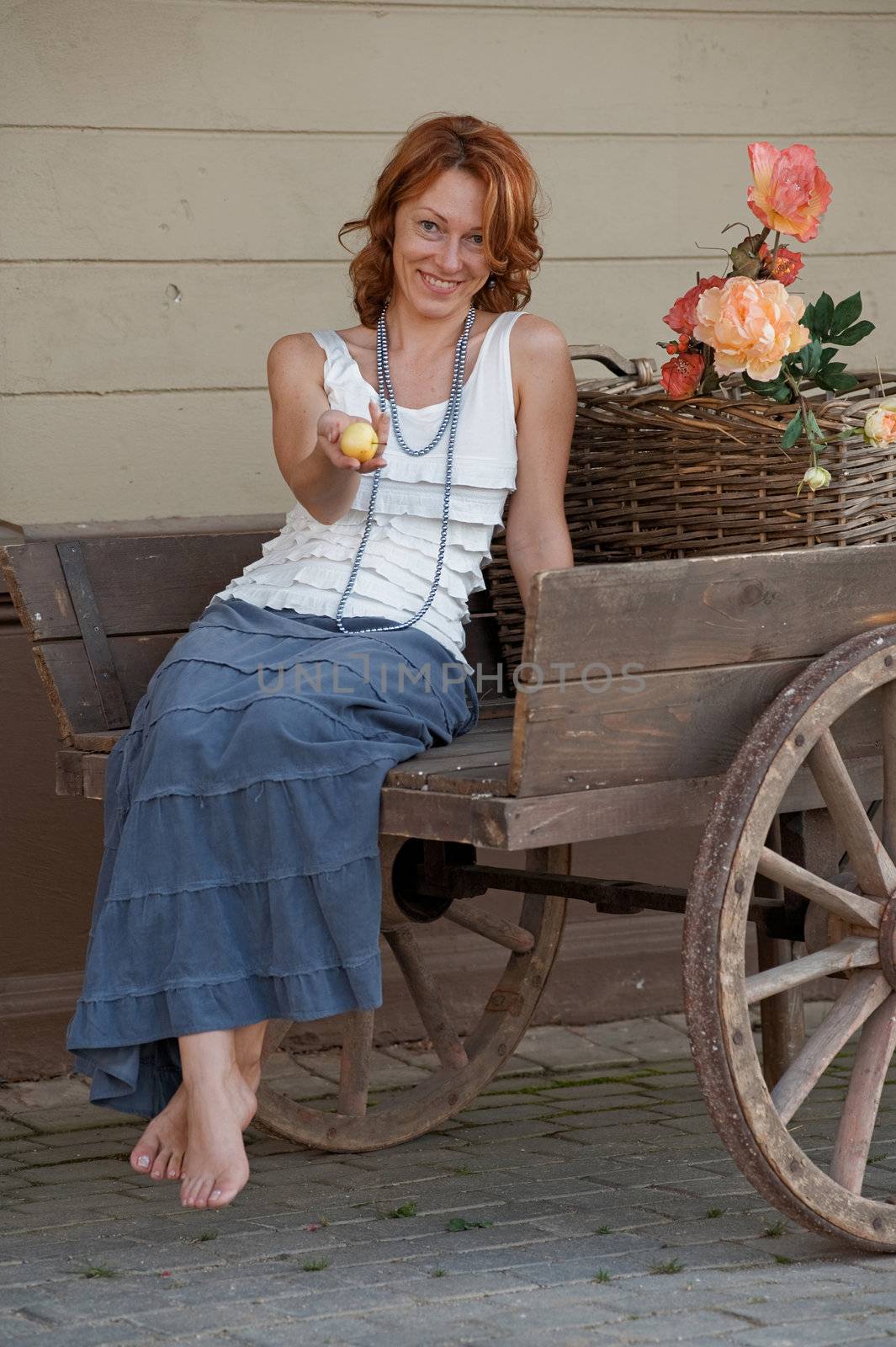 Adult smiling women with apple in hand sitting in old retro cart