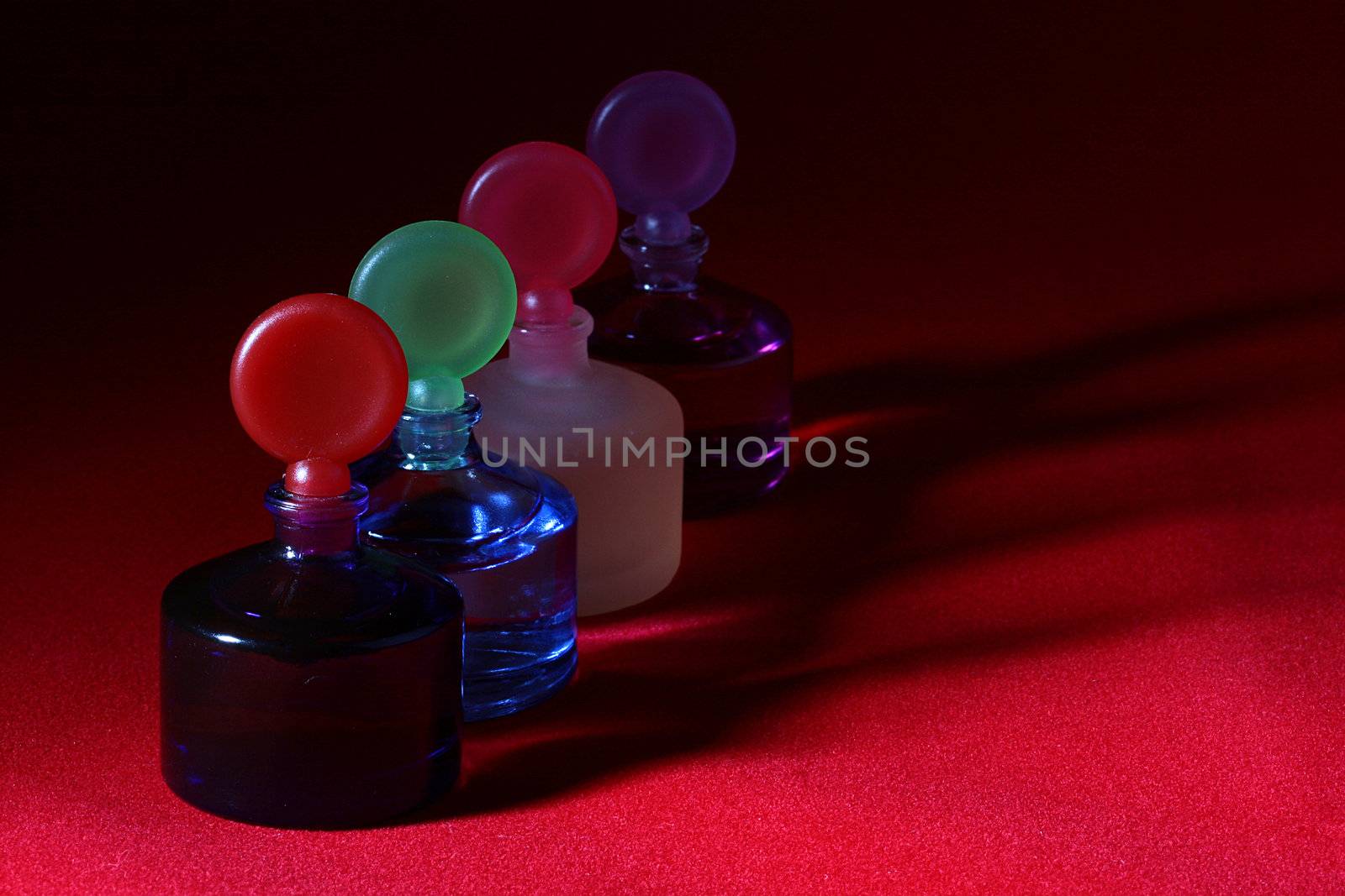 Colour bottles of the small size for cosmetics storage on a red background.