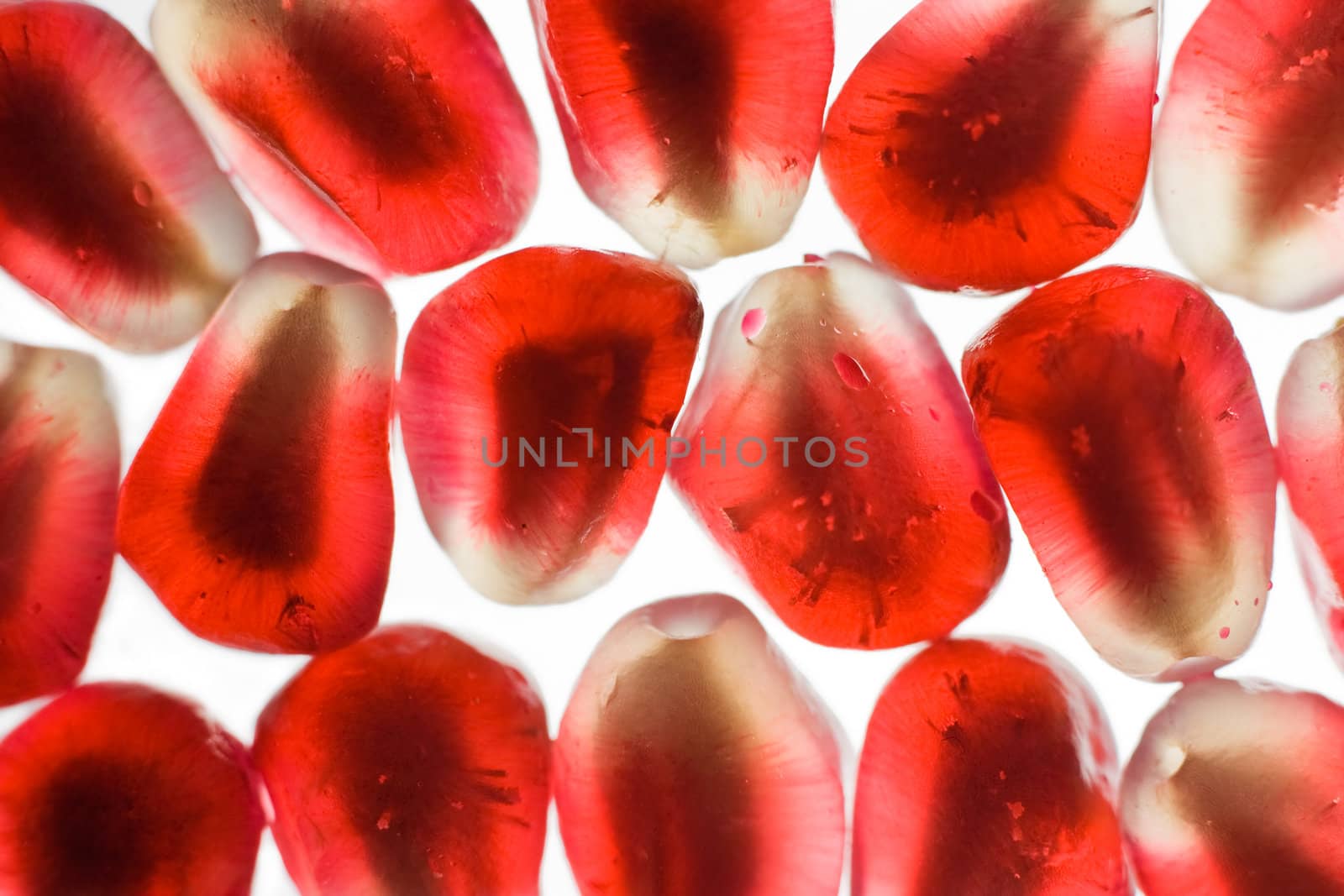 Bright translucent juicy pomegranate grain, arranged in linear order a solid background, close up, isolated on a white background