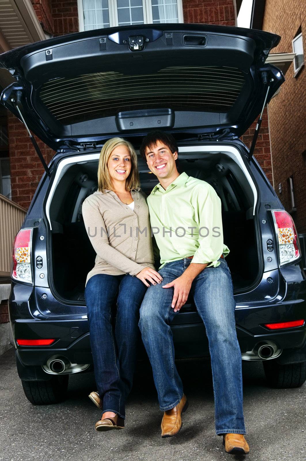 Happy young couple sitting at back of car