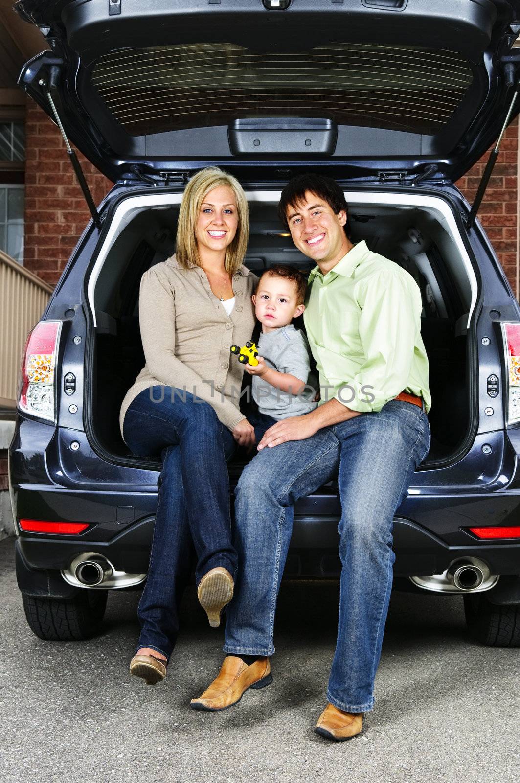 Happy young family sitting at back of car