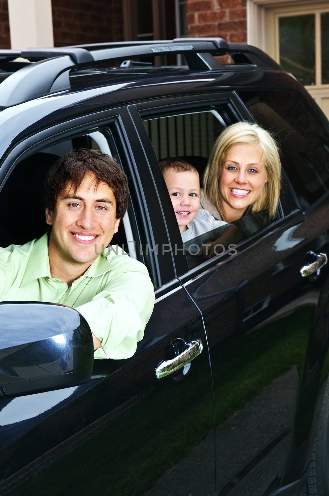 Happy young family sitting in black car looking out windows