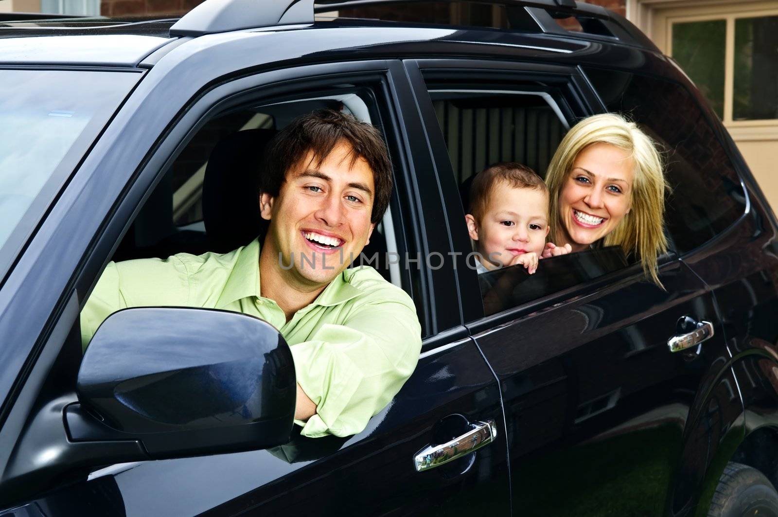 Happy young family sitting in black car looking out windows