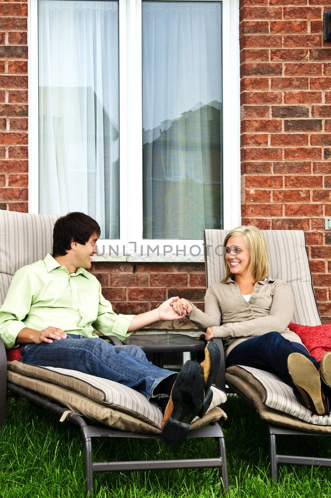 Happy couple in backyard of new home sitting on lounge chairs