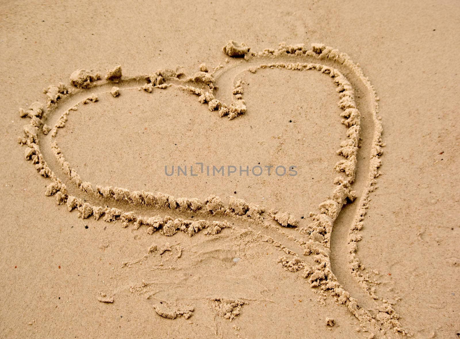 a love heart drawn in the sand at the beach