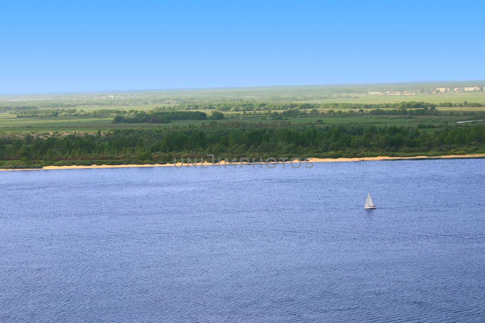 The yacht on a water smooth surface removed against a large forest