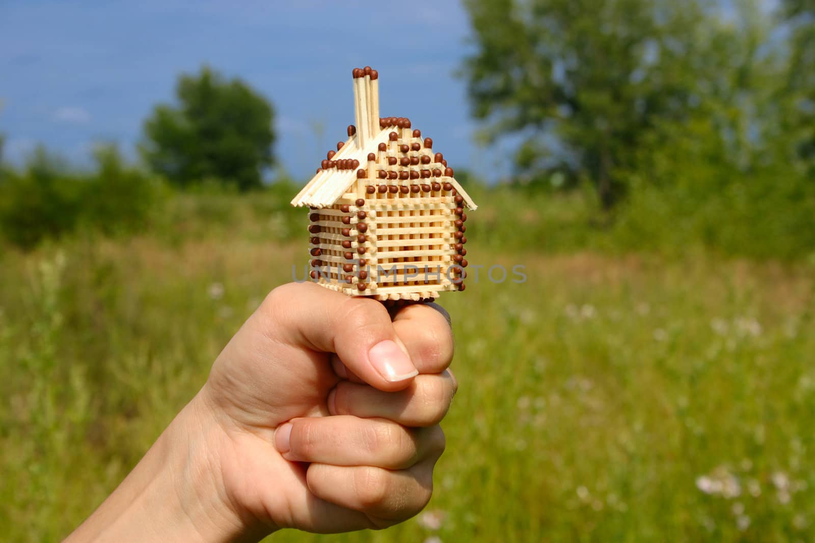 Match small house standing on a female fist removed close up