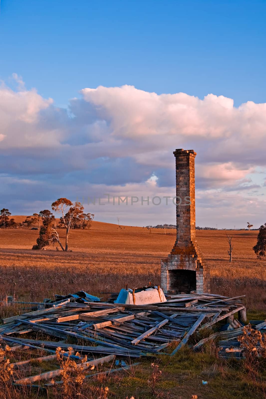 all that is left of this old farmhouse is a chimney, a pile of wood and an upturned bath