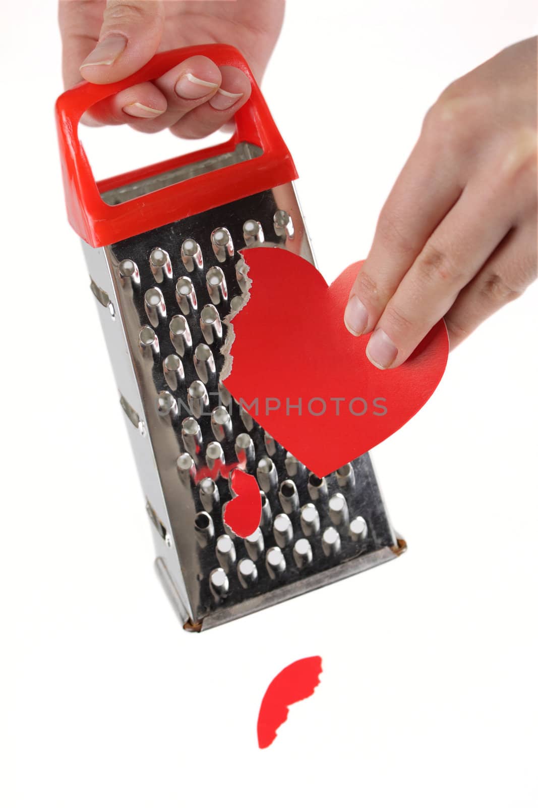 Female hands rubbing red paper heart on a kitchen grater