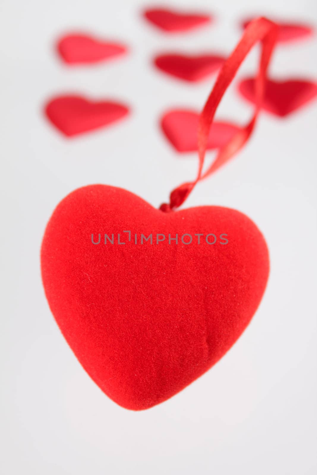 Red plush heart against small hearts removed close up