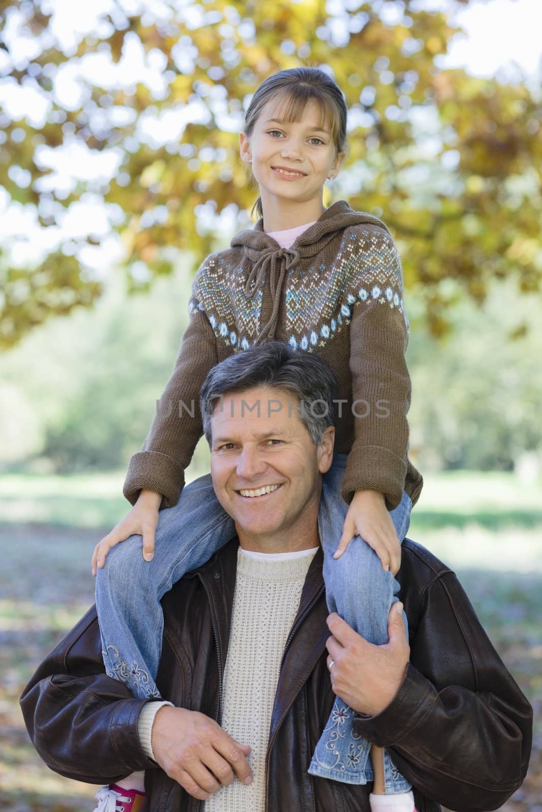 Portrait of a Father Holding Daughter on His Shoulders in a Park