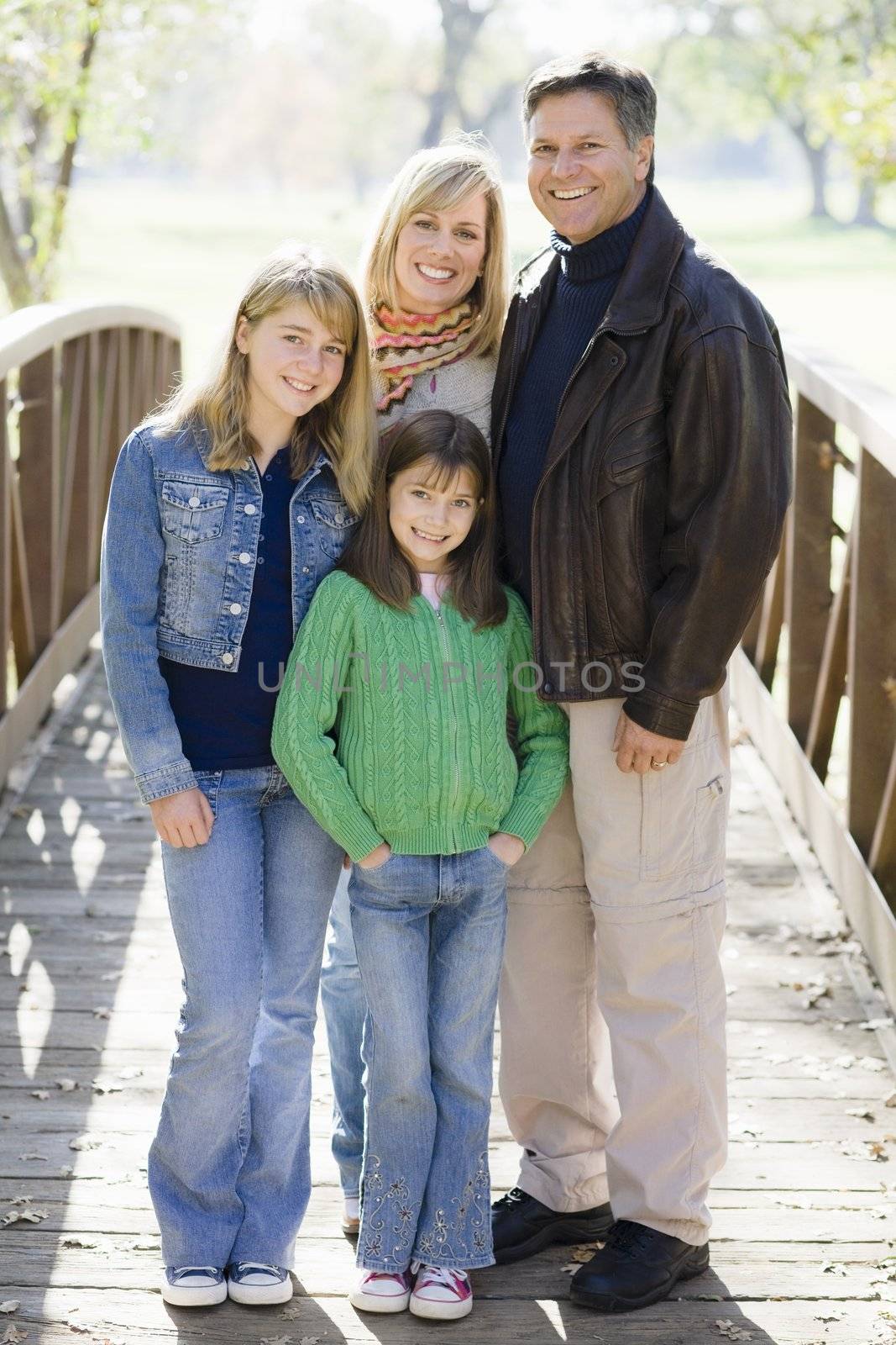 Portrait of Smiling Parents and Two Daughters Standing on a Bridge
