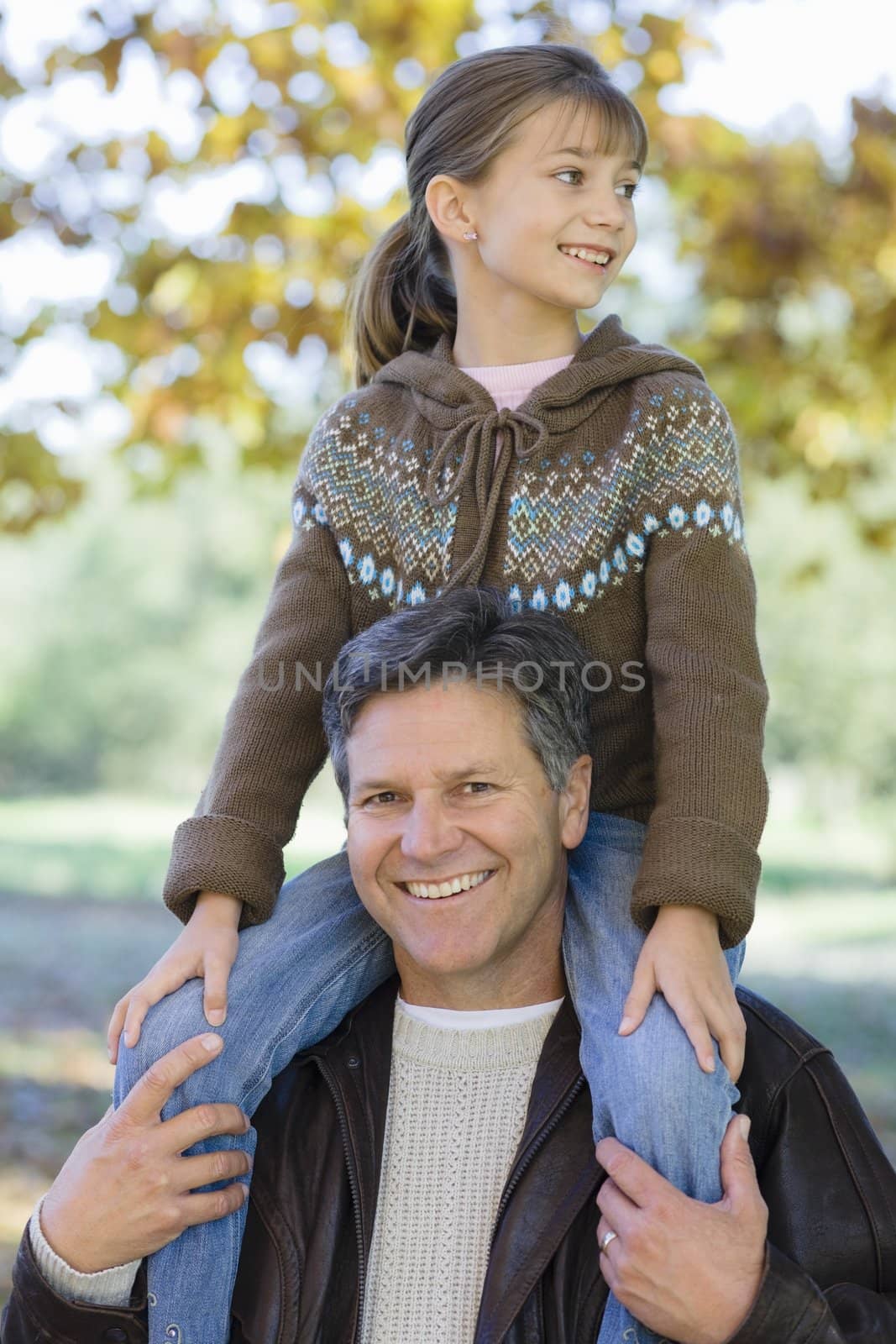 Portrait of a Father Holding Daughter on His Shoulders in a Park