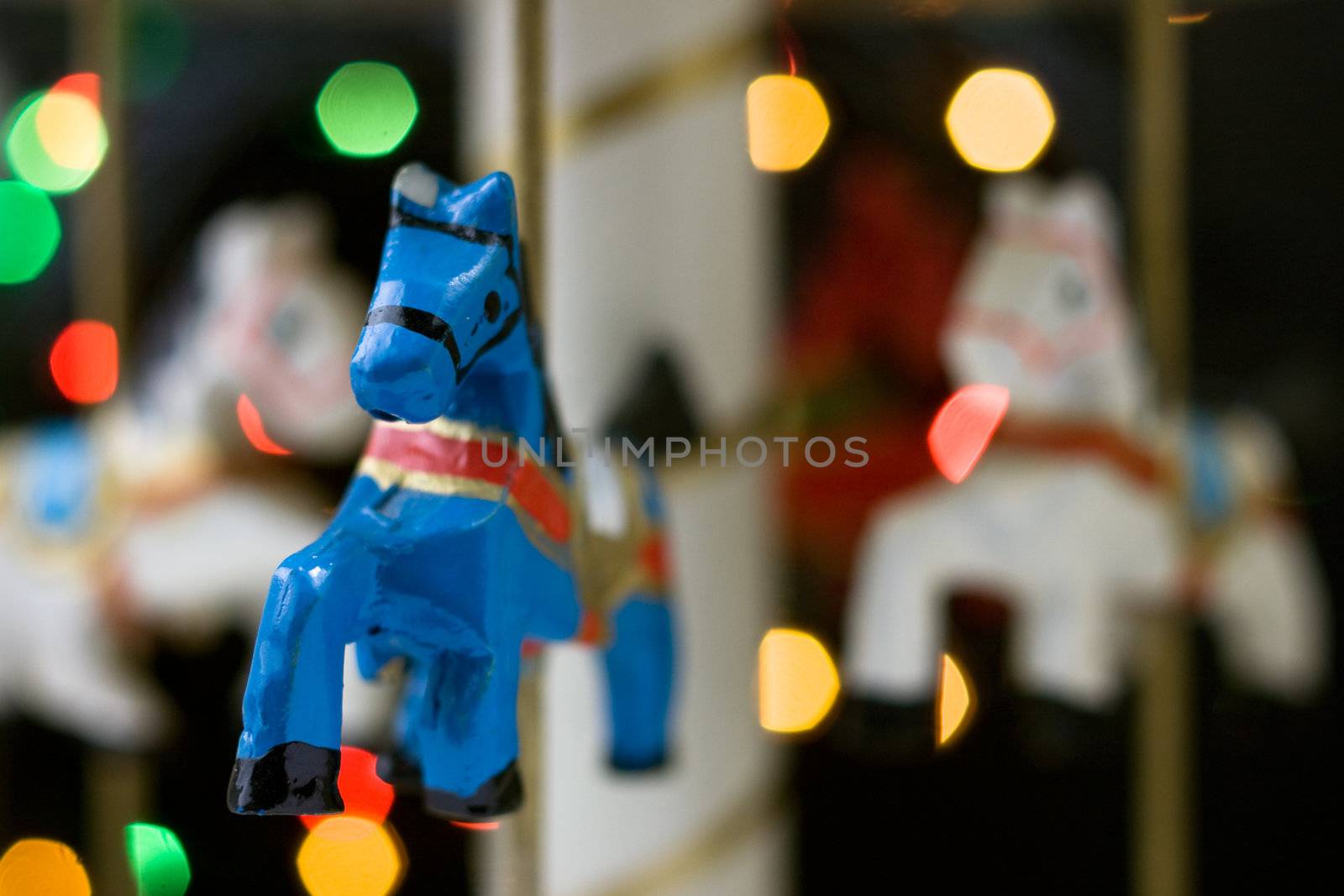 Miniature carousel with horses, against the background of New Year's lights. Depth of field for strong emotions.