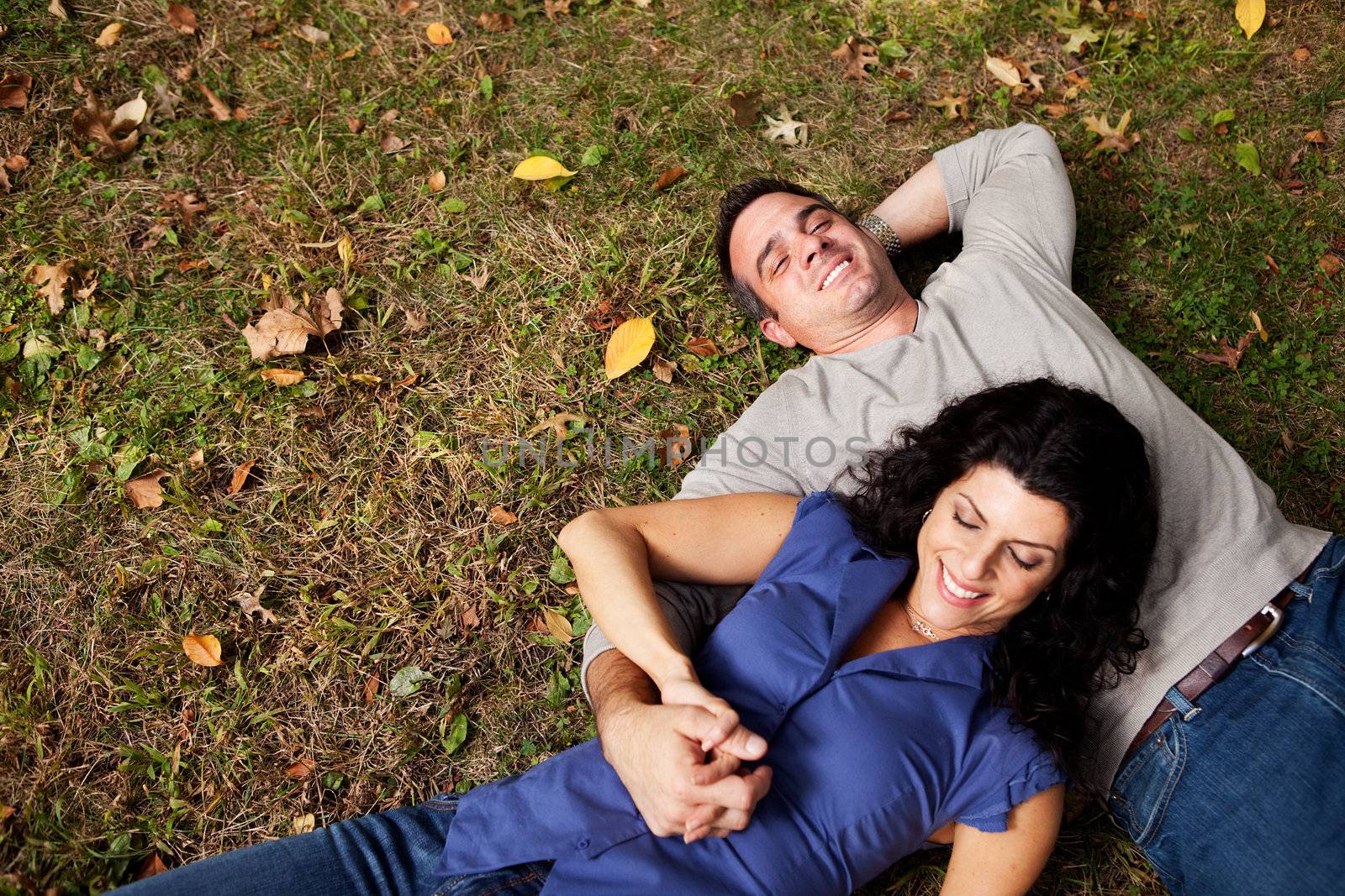 A happy couple daydreaming in a park on grass - sharp focus on man