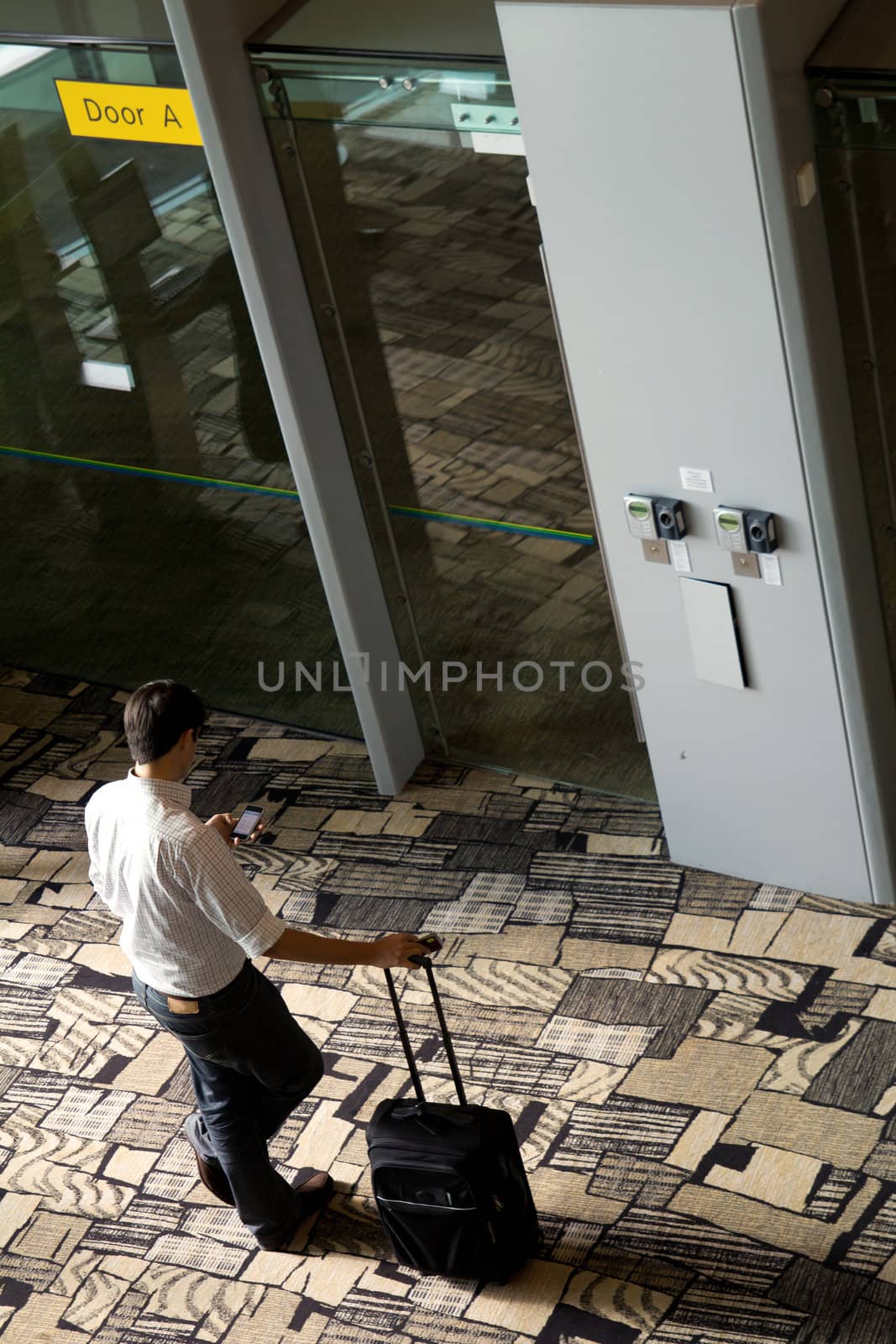 High angle view of a man texting at airport by Kenishirotie