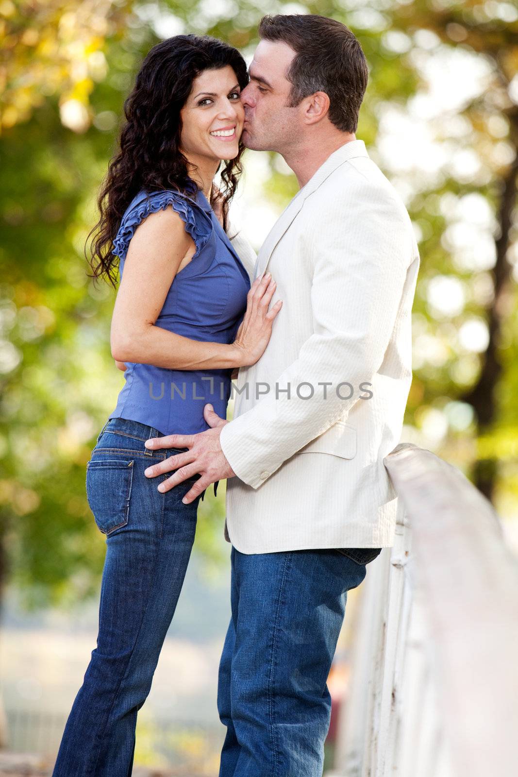 A man kissing a woman on the cheek in a park