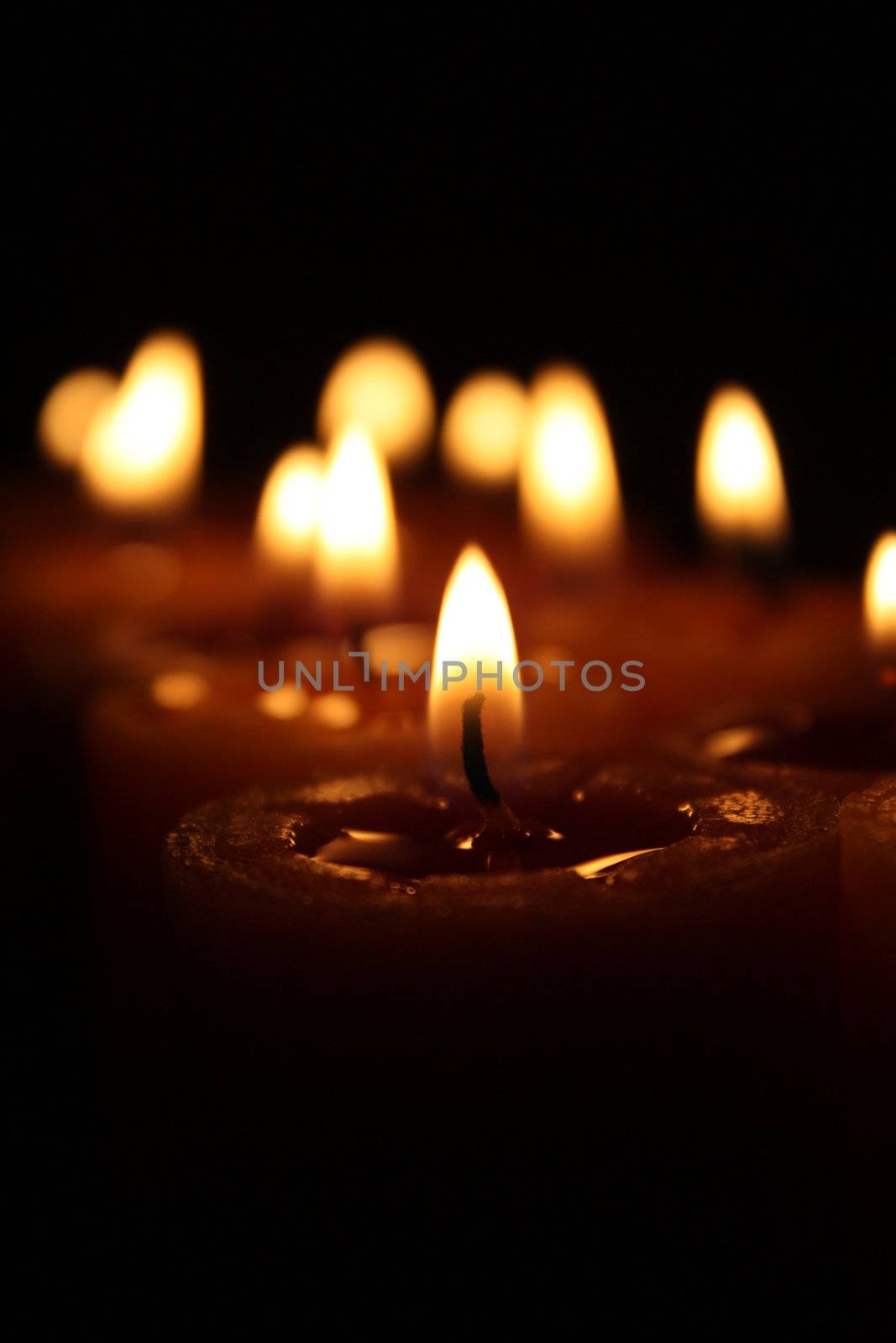 Burning aroma candle in focus and other candles out of focus