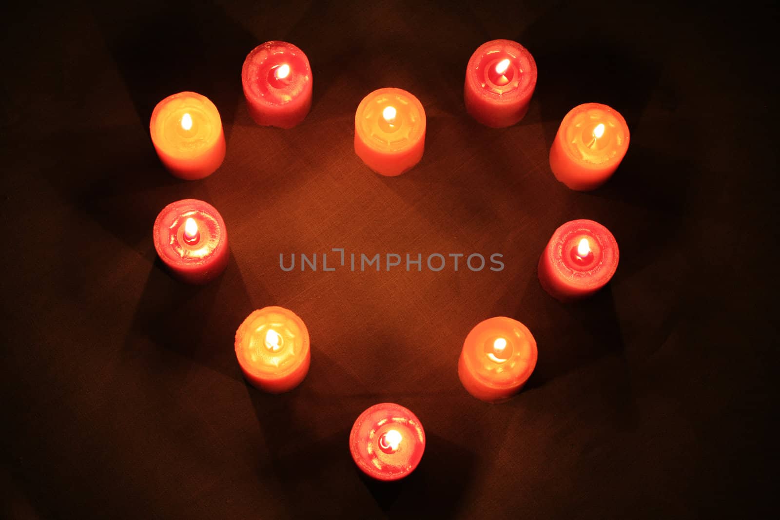 Some candles in heart-shaped composition on linen background