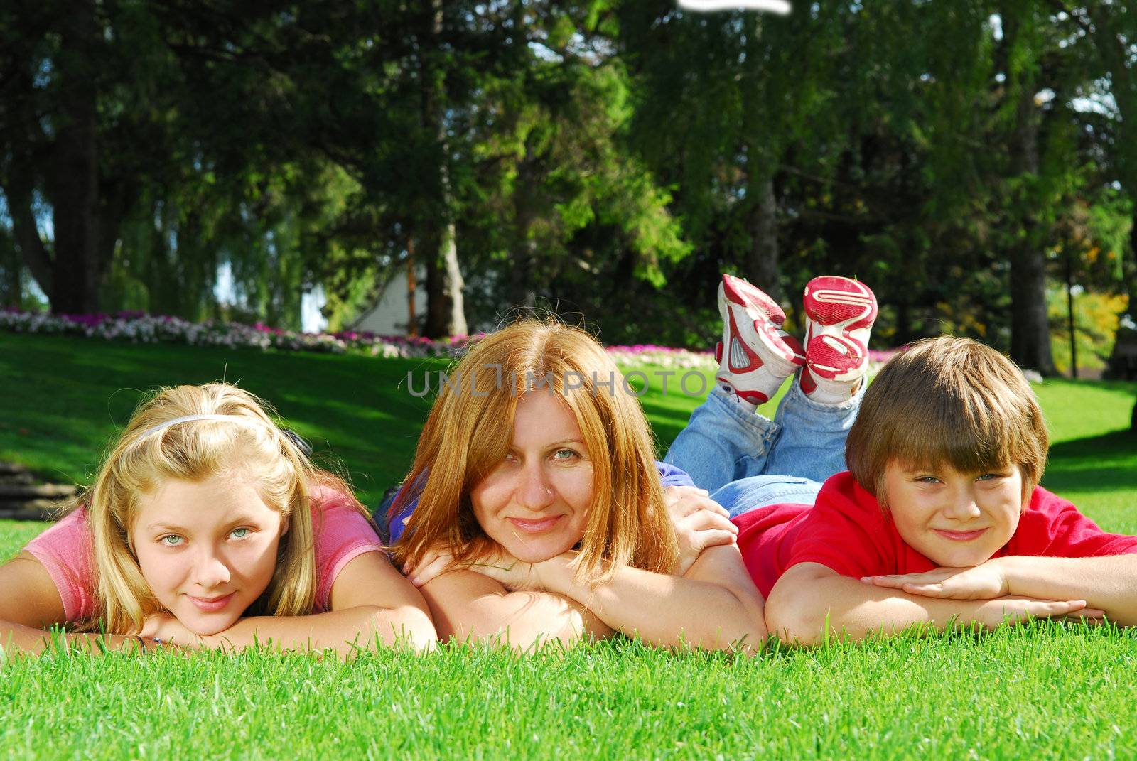 Family of happy mother and children relaxing on green grass