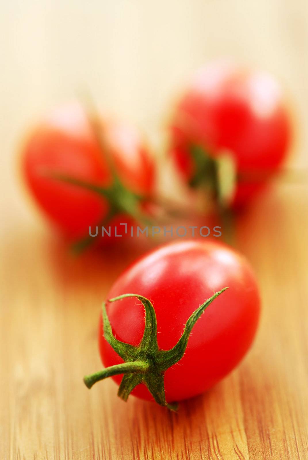 Small grape or cherry tomatoes on wooden cutting board