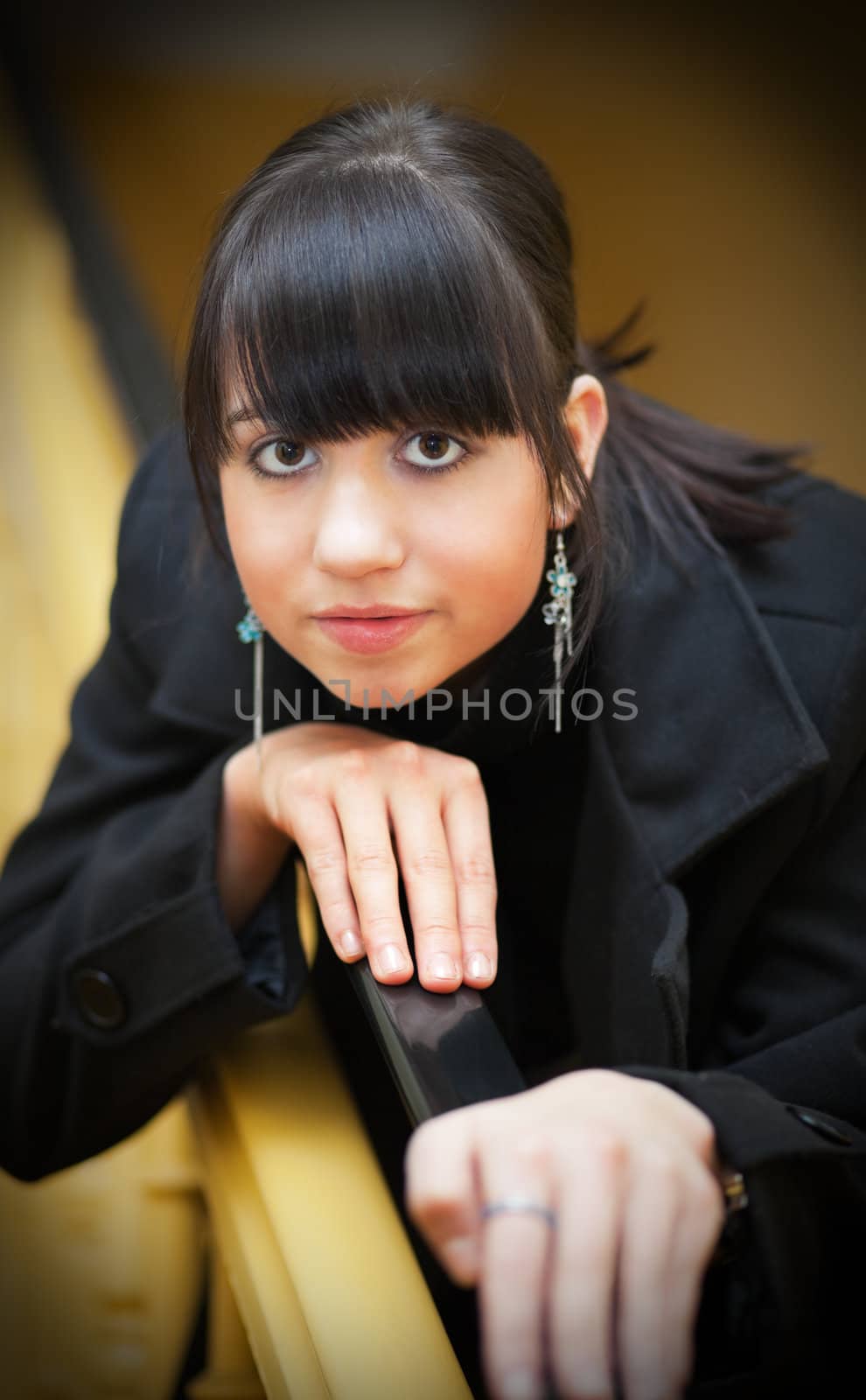 Pretty brunette girl leaning on stair rail; photographed indoors