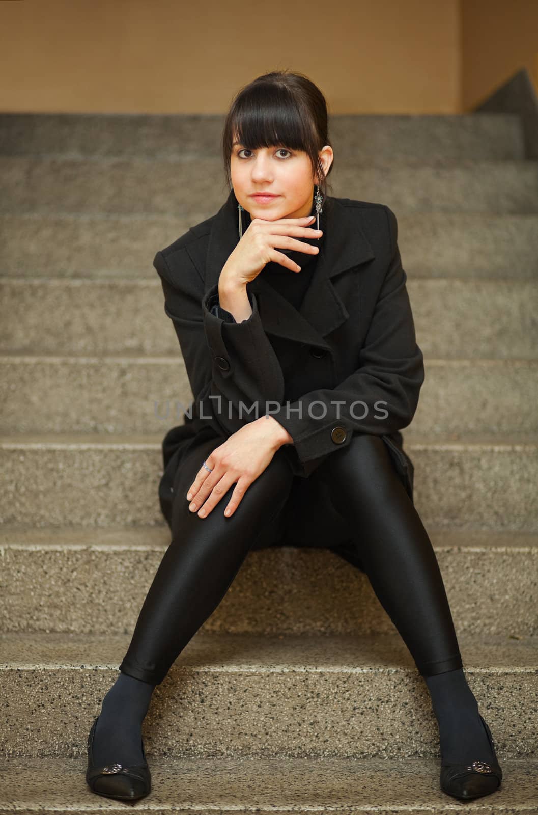 pretty brunette girl dressed in black clothes sitting on stair step