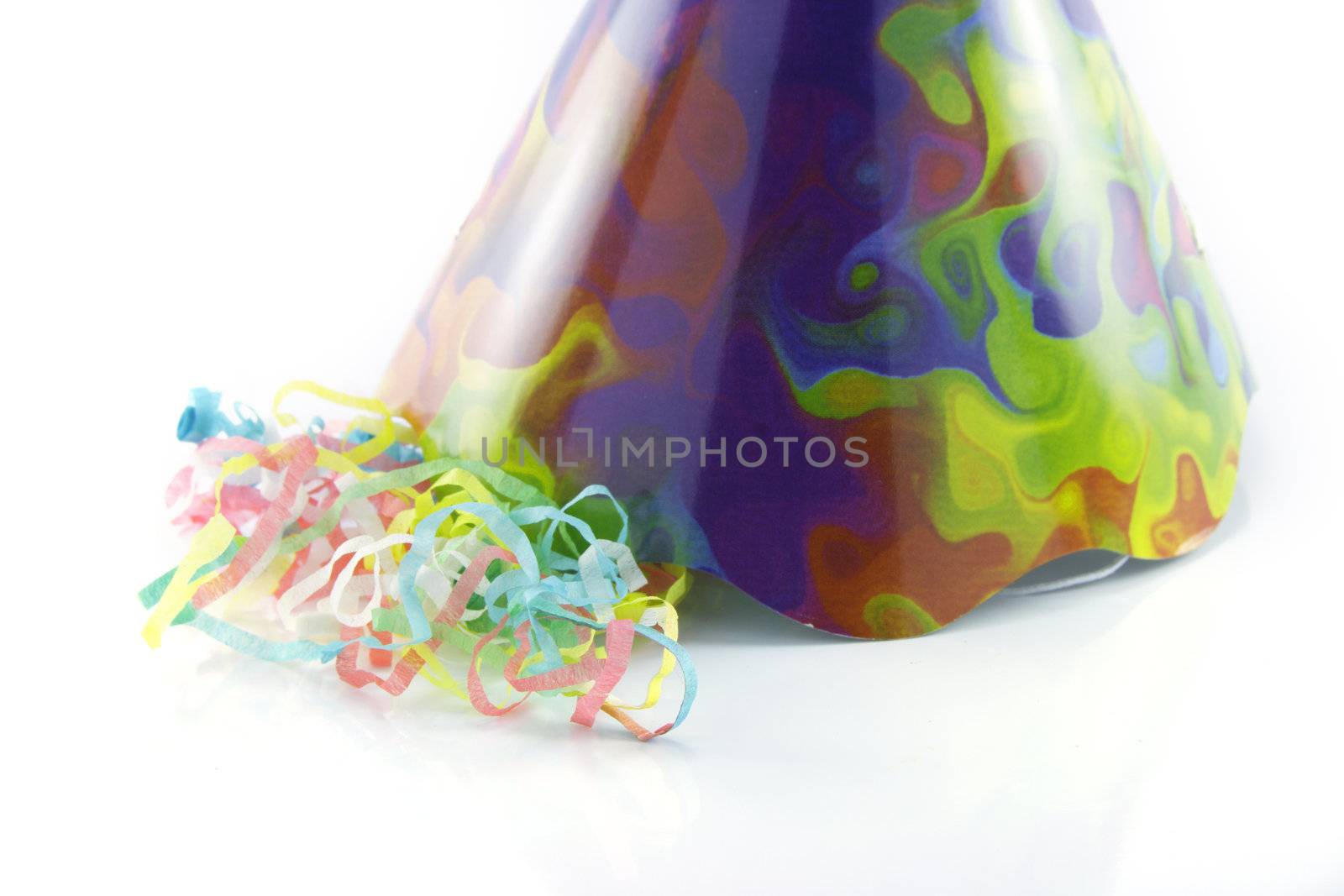 Bright cone shaped party hat with party streamers on a reflective white background