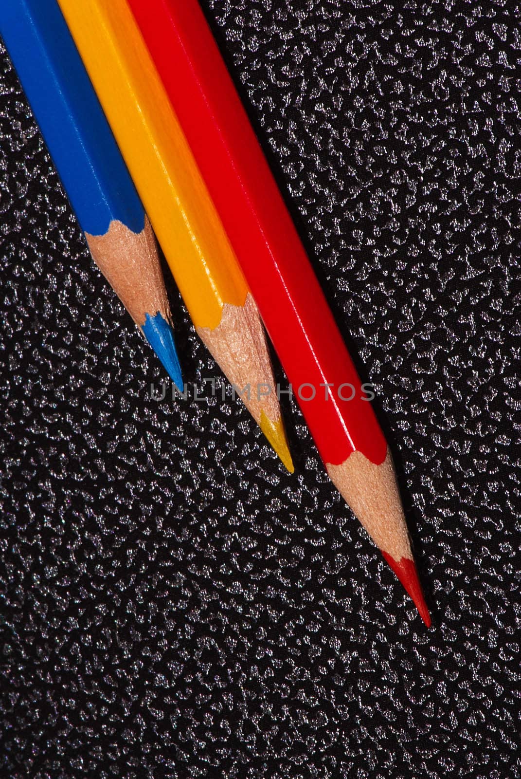 Red, blue and yellow pencils on surface from  artificial leather. A close up