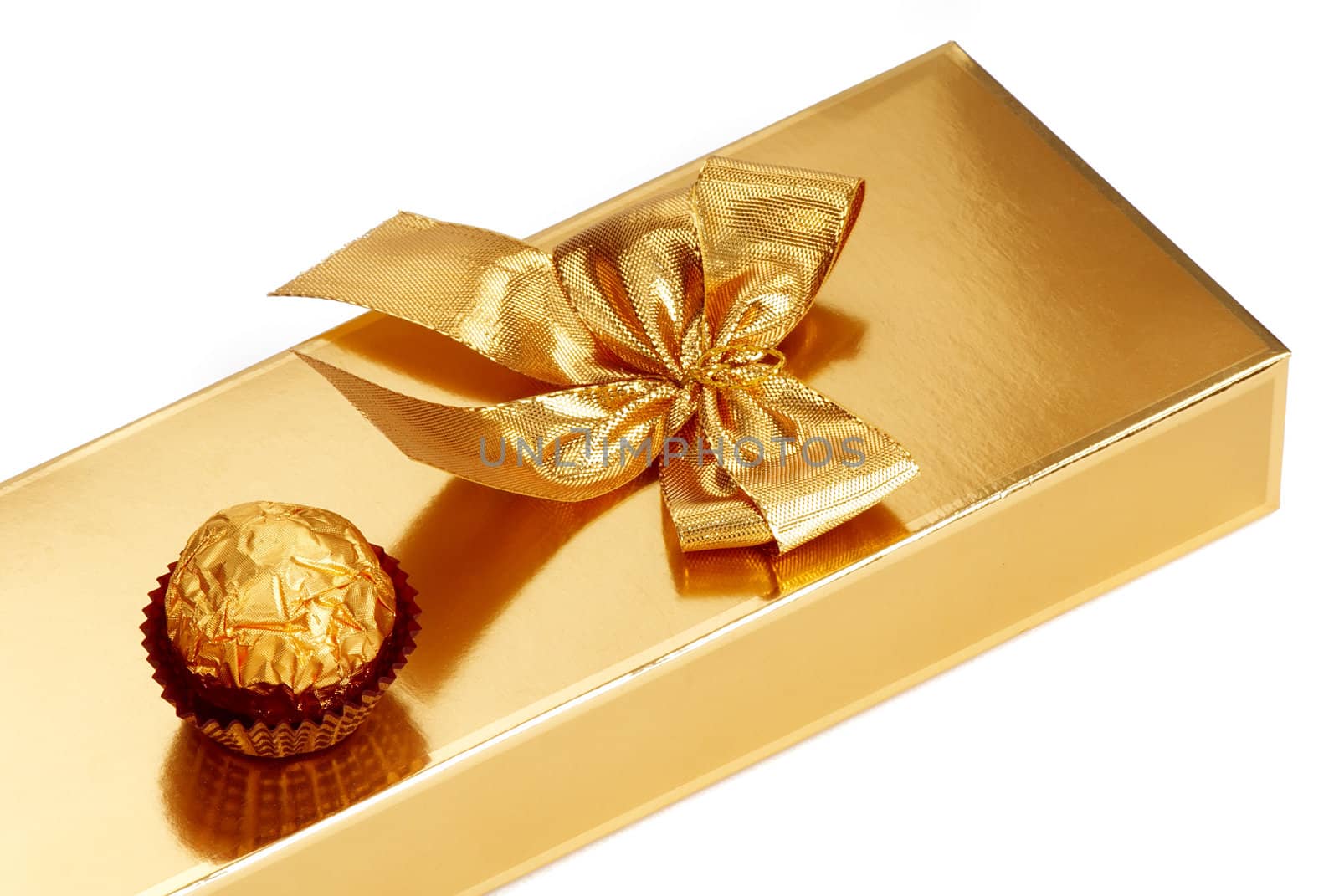 A gold boxed gift with gold ribbon and chocolate.