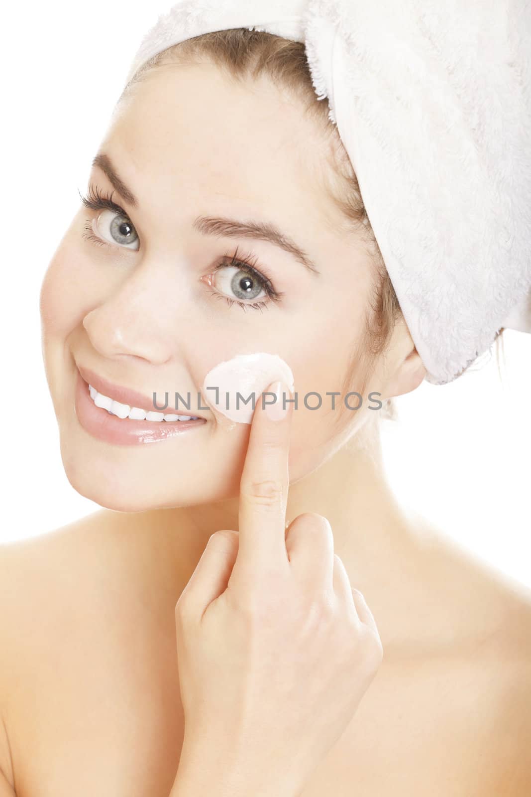 Beautiful smiling woman applying moisturizer cream on her face. Isolated on white background