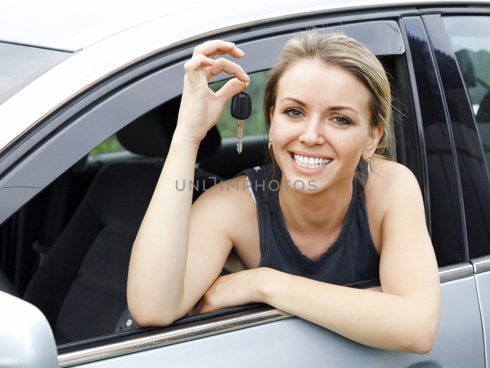 Beautiful young happy woman in car showing the keys by Nobilior