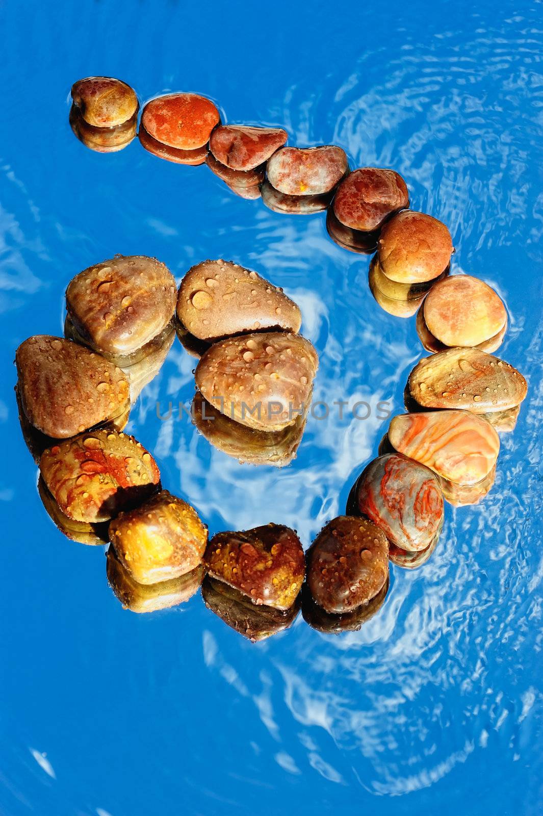 Spiral of colored stones on the water surface