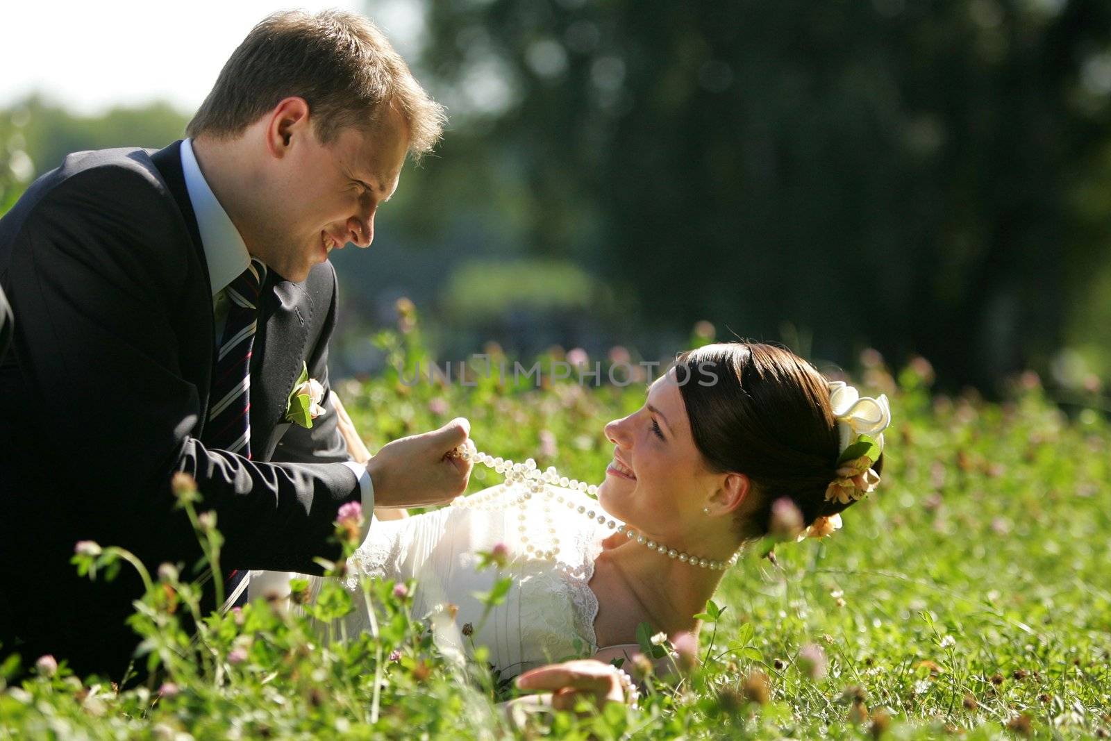 Newlywed young couple romancing in summer meadow outdoors.
