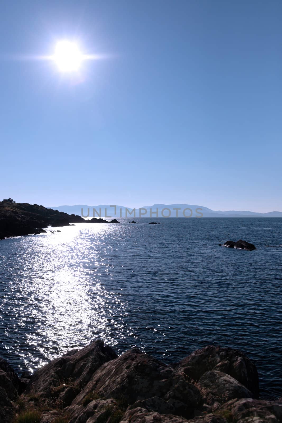scenic view in kerry ireland of rocks and sea with mountains against a beautiful bright sunny sky