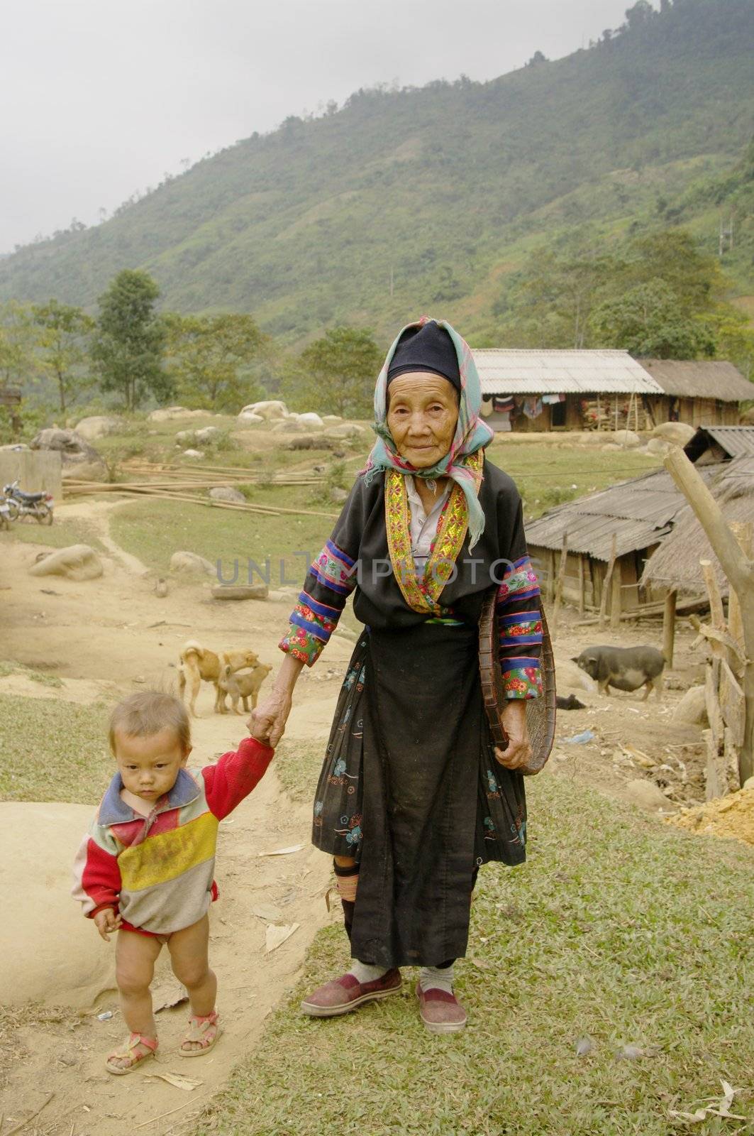 A grandmother of Phu La ethnic walking his grandson  in the village.