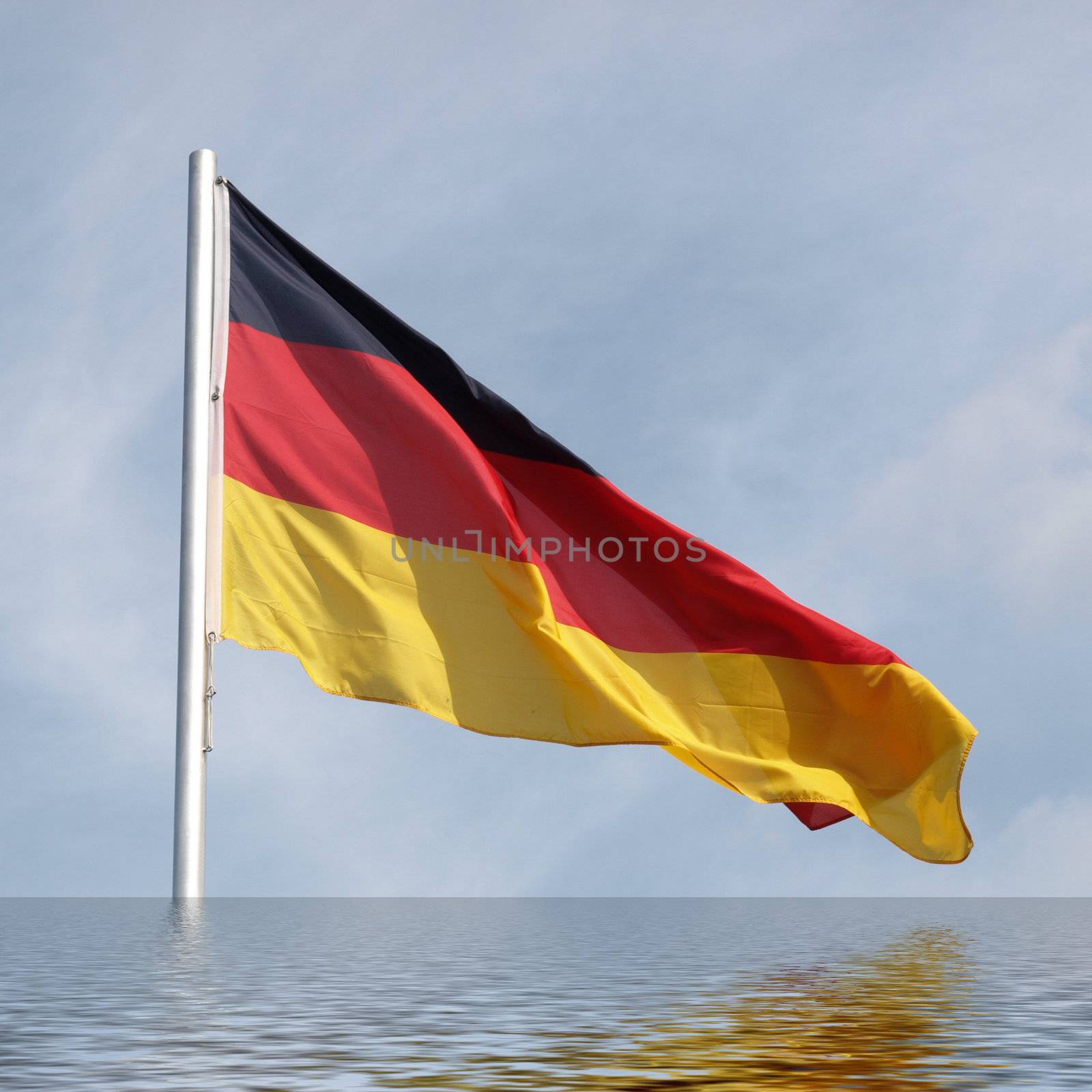 Flag of Germany over a blue sky reflected in water