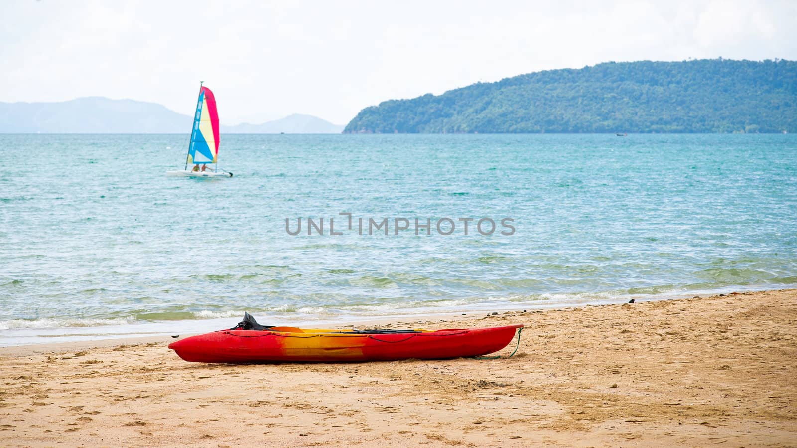 Sailing-boat in the sea and kayak on the beach