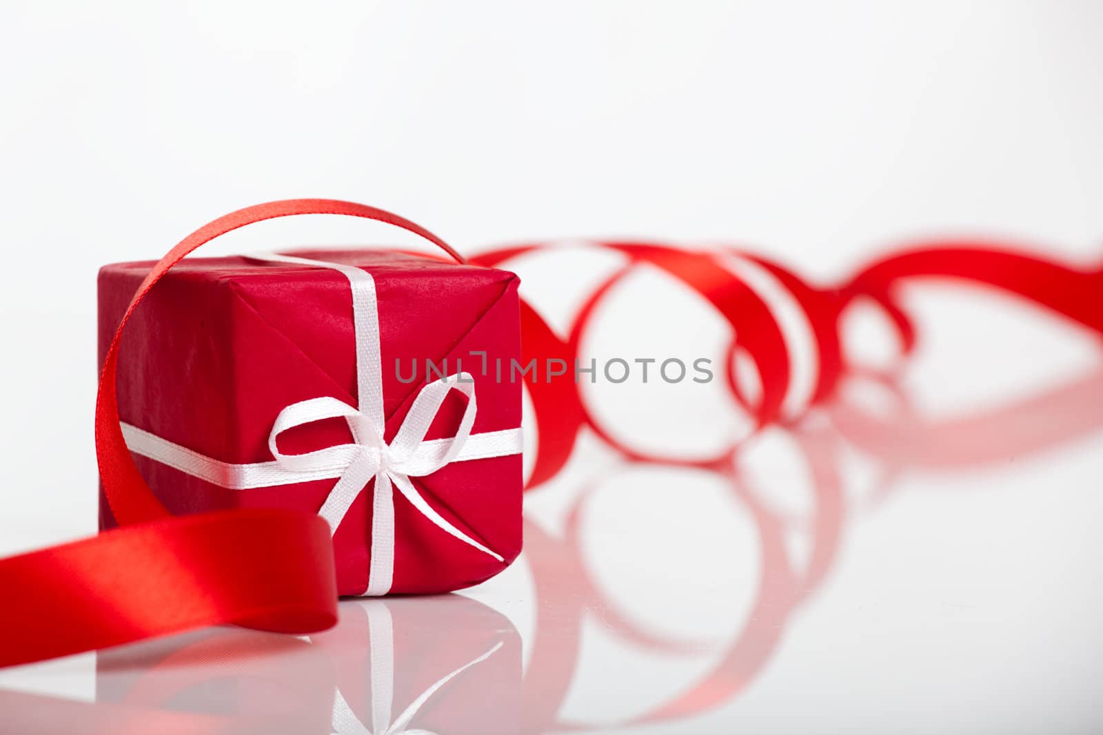 Red gift with a red ribbon over the gift, isolated on white background