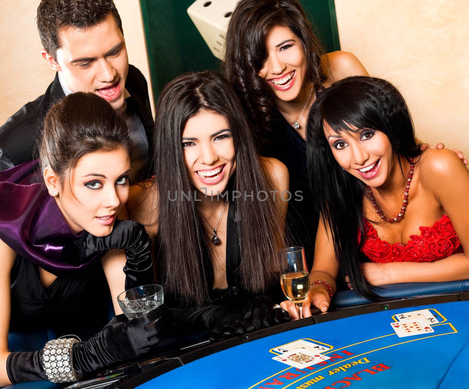Group of young happy people in casino smiling behind black jack table